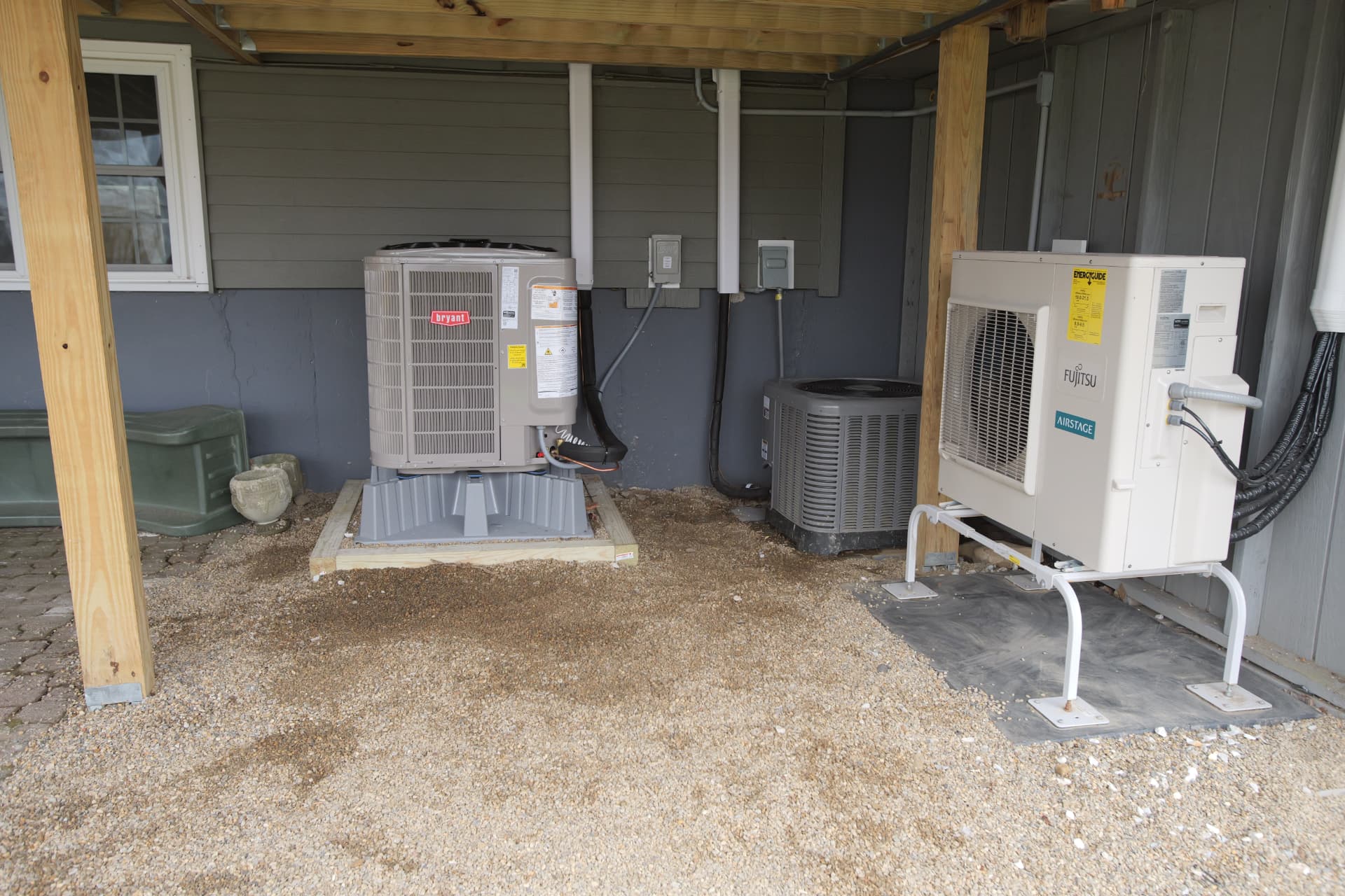 Bryant and Fujitsu outdoor units installed beside a home
