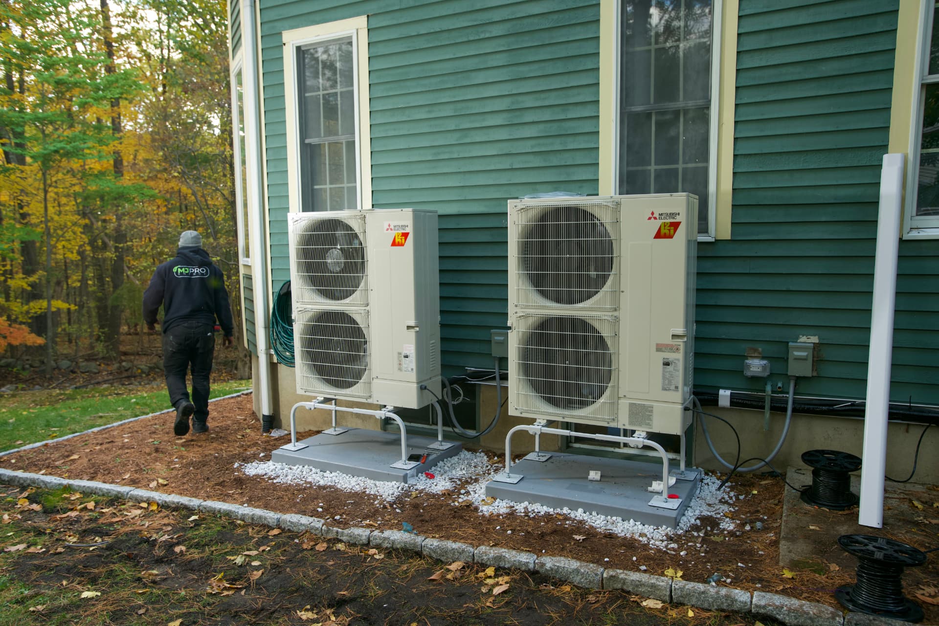 Two Mitsubishi heat pump outdoor units installed beside a home