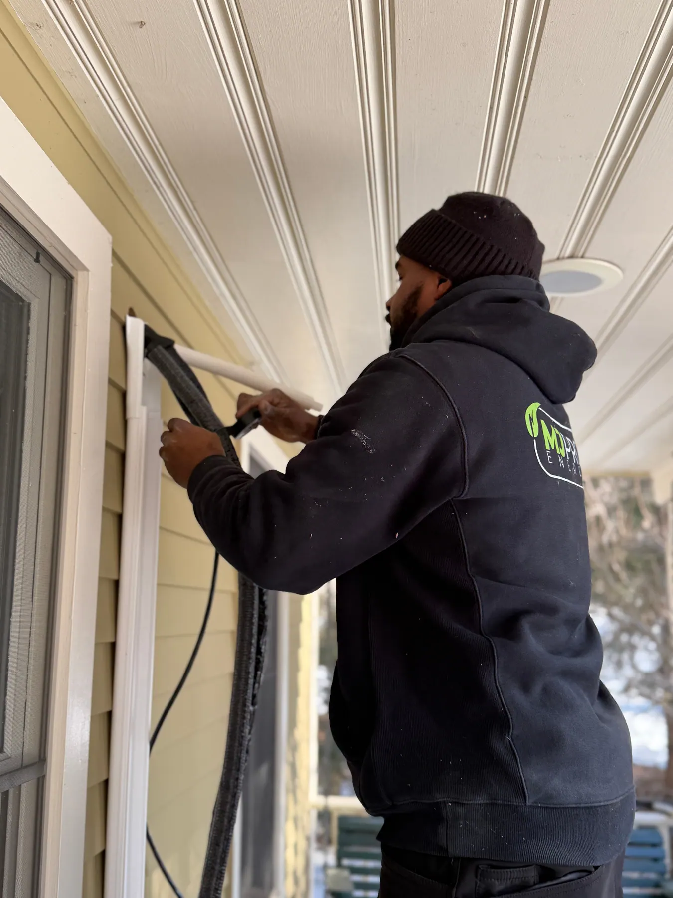 MJ Pro Energy technician running mini split line set on a Massachusetts home